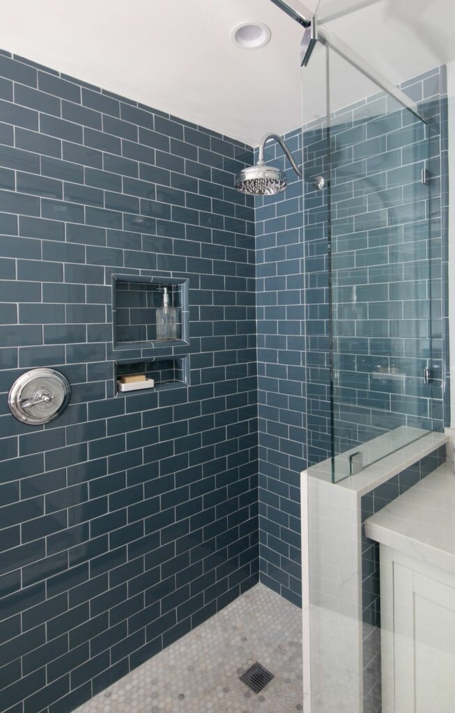 Custom blue subway tile shower installation with recessed niche in Los Angeles